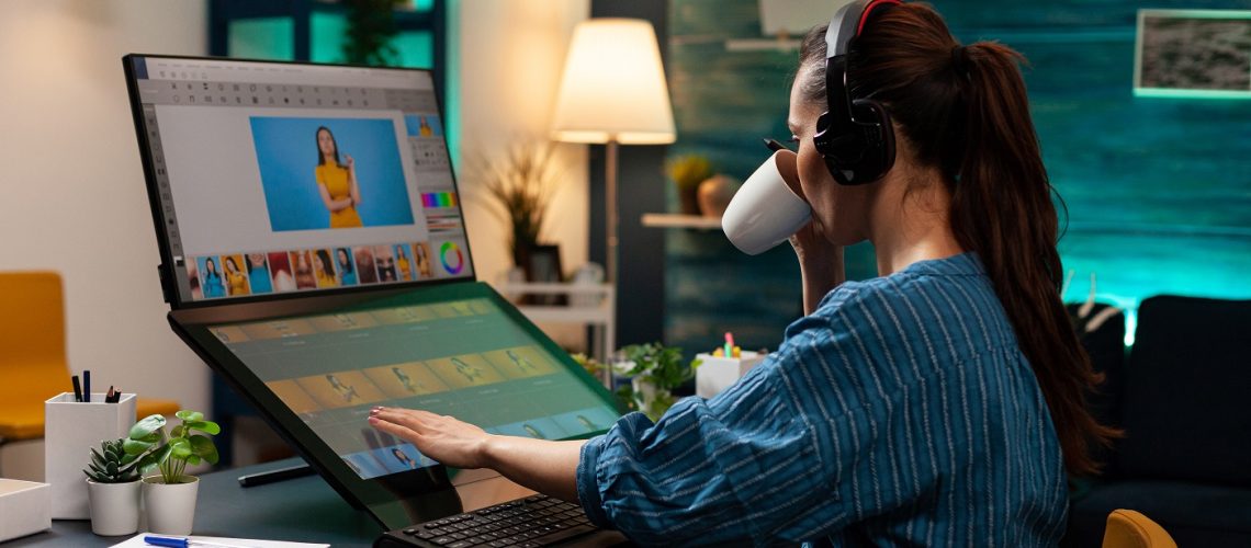 Woman with editor occupation wearing headphones at studio office desk. Professional graphic artist working on picture editing background for template using touchpad monitor screen